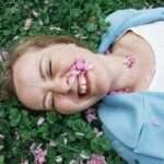 smiling girl white girl on grass flowers on face